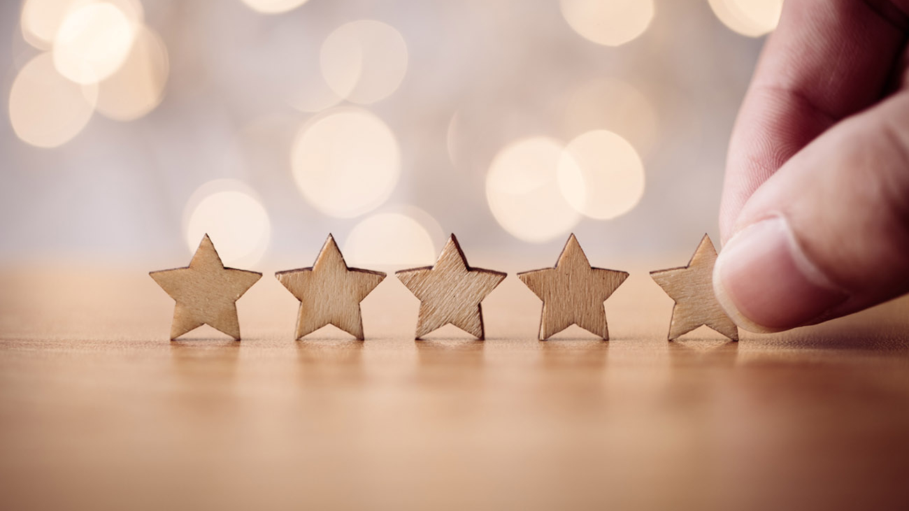 Hand putting wooden five star shape on table. The best excellent business services rating customer experience concept.